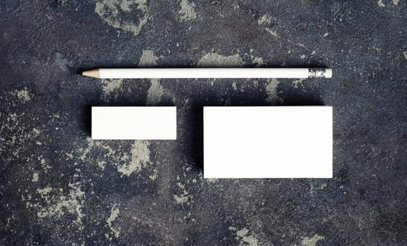 Blank business card, pencil and eraser on concrete background. Stationery mockup. Top view. Flat lay.