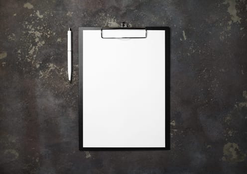 Clipboard with blank paper and pen on concrete background. Responsive design mockup. Top view with copy space. Flat lay.