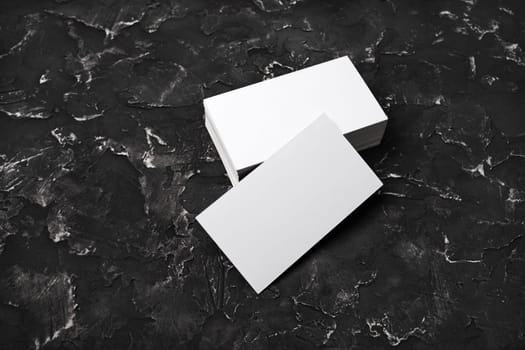 Photo of blank business cards on black plaster background. For design presentations and portfolios.