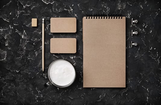 Blank kraft stationery set on black plaster background. Template for branding identity. Top view. Flat lay.