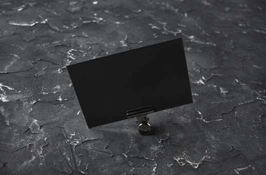 Photo of blank black business card on black plaster background. Mock-up for branding identity.