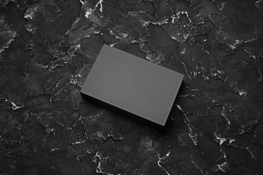 Stack of gray business cards on black plaster background.