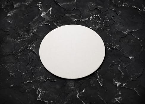 Blank white beer coaster on black plaster background. Responsive design mockup.