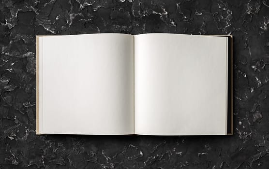 Open blank book on black plaster background. Top view with copy space. Flat lay.