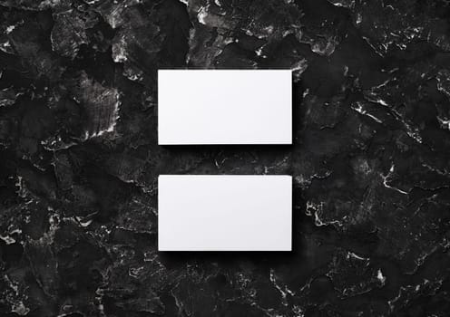 Two blank white business cards on black plaster background. Mockup for branding identity. Flat lay.