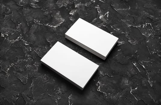 Two stacks of blank business cards on black plaster background. Mockup for branding identity.