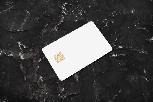 Photo of blank bank card on black plaster background. Photo of white credit card.