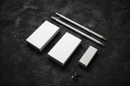 Blank business cards, pencils and eraser on black plaster background. Stationery mockup. Objects for placing your design.