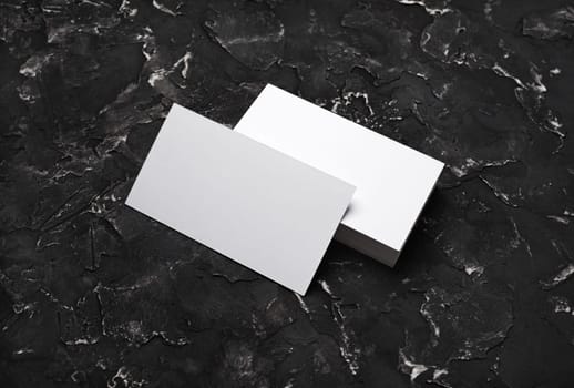 Blank white business cards on black plaster background. Mockup for branding identity. Template for graphic designers portfolios.
