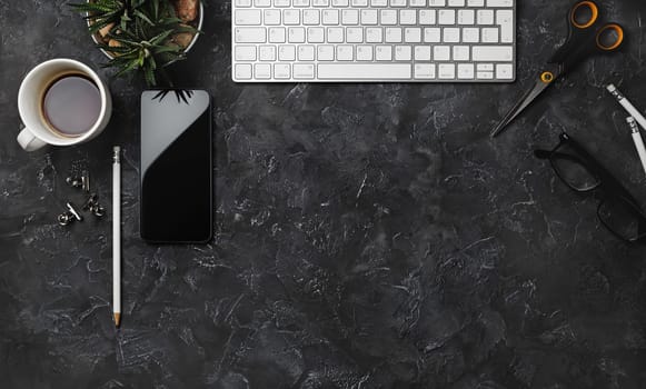 Office supplies and gadgets on black plaster background. Copy space for your text. Flat lay.