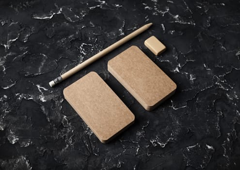 Blank kraft business cards, pencil and eraser on black plaster background. Mockup for branding identity.