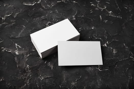 Blank white business cards on black plaster background. Mockup for branding identity.