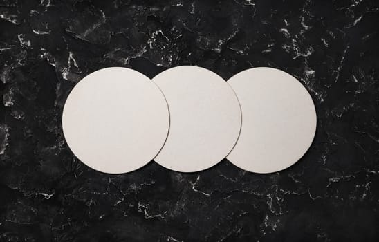 Three blank beer coasters on black plaster background. Responsive design mockup. Top view with copy space. Flat lay.