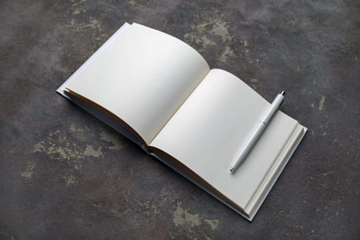 Blank open brochure and pen on concrete background. Responsive design template.