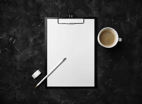 Photo of clipboard with blank letterhead, coffee cup, pencil and eraser on black plaster background. Blank stationery template. Flat lay.