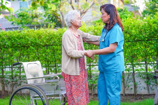 Caregiver help Asian elderly woman disability patient sitting on wheelchair in park, medical concept.