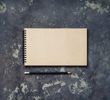 Photo of blank vintage sketchbook and pencil on concrete background. Copy space for text. Top view. Flat lay.