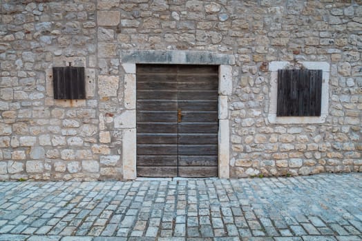 Stone wall with doors and windows. The traditional look of a Mediterranean city.