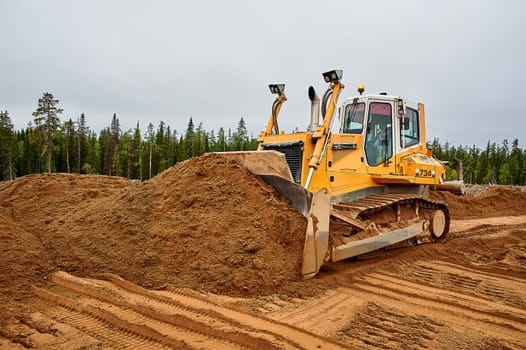 A yellow tractor levels the site with sand. High quality photo