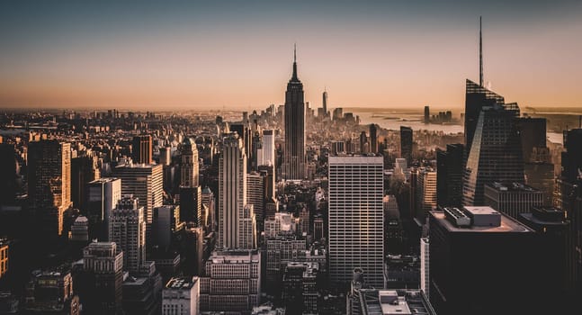 New York City. Manhattan downtown skyline with illuminated Empire State Building and skyscrapers at sunset.