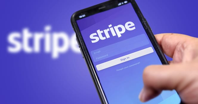 San Francisco, CA, USA, March 15, 2021: Stripe's application login page on the screen of a hand held smartphone. Background with blurry Stripe logo. Stripe is an American financial services company