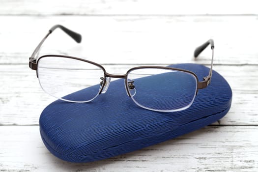 Stylish eyesight glasses and case for glasses on white wooden table