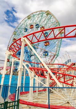 Red Rollercoaster at Luna Park Amusement Park with Wonder Wheel Ferris Wheel, Coney island, Brooklyn, close-up, New York City during winter day with cloudy sky, No People, vertical