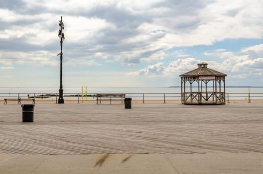 Empty Beach Promenade at Coney island, Brooklyn during sunset with ocean and cloudy Sky, Beach Pavilion at the Promenade, New York City during winter day with cloudy sky, horizontal