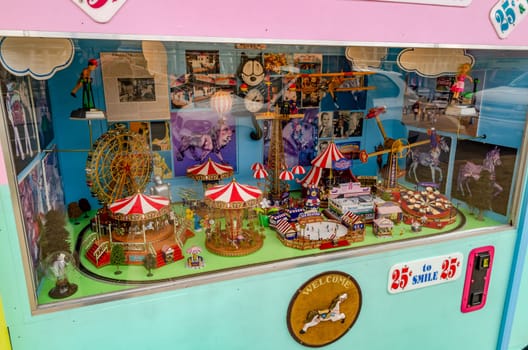 Retro Old vending machine at Luna Park Amusement Park, Coney island, Brooklyn with different miniature Rides visible through a window, New York City during winter day, horizontal