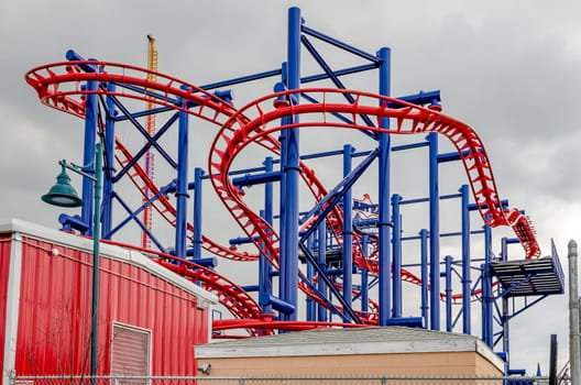 Soarin' Eagle Rollercoaster at Coney island, Brooklyn, New York City during winter day with cloudy sky, view from low angle, buildings in front, horizontal