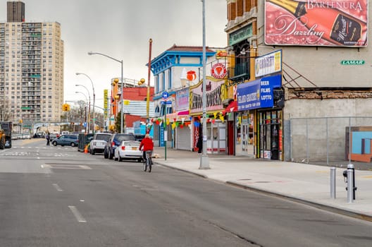 Stores and Restaurants at City Street in Coney island, Brooklyn, New York City during winter day with cloudy sky, Cars parked next to the street in front of the stores, Residential Building in the Background, horizontal