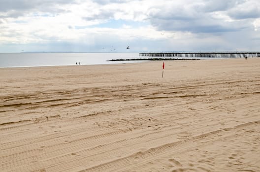 Beach at Coney island, Brooklyn with Ocean and Pat Auletta Steeplechase Pier, New York City during winter day with cloudy sky, almost no People at the Beach, horizontal