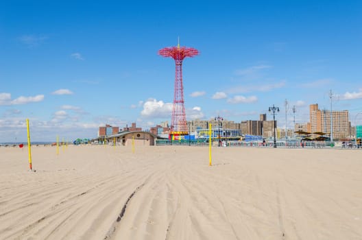 Parachute Jump at Luna Park Amusement Park, Coney island, Brooklyn with empty sand Beach in front during sunny winter day with clear sky, New York City, Residential Buildings in the background, horizontal