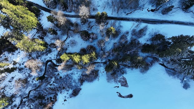 Aerial drone shot of snowy landscape with stream and road