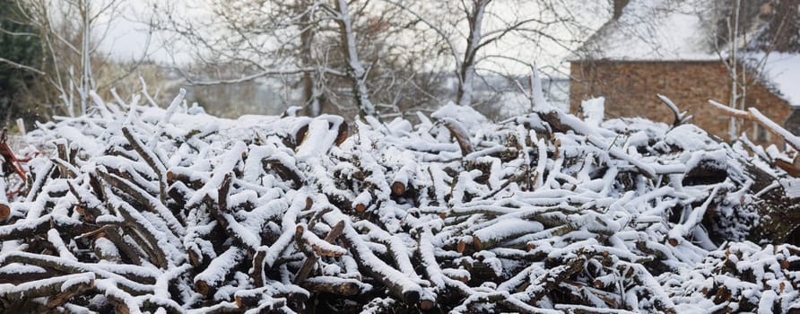 Large firewood stack in wintertime covered with cold snow