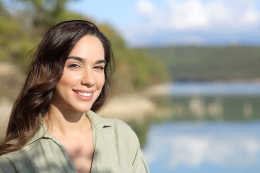 Happy woman looking at camera posing in a lake