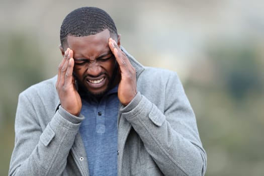 Stressed man with black skin suffering migraine in winter