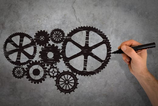 Hand drawing black gears on gray wall