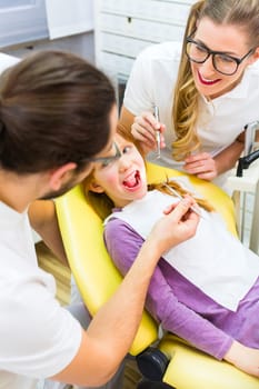 Dentist and assistant treat patient in dental practice