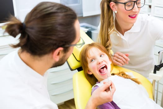 Dentist and assistant treat patient in dental practice