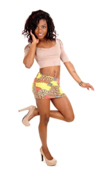 A pretty African American woman in a short skirt a t-shirt with heels.standing in profile isolated for white background..