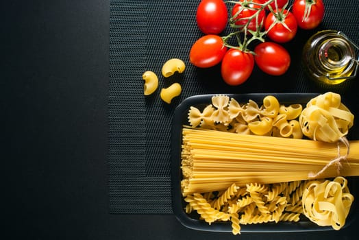 Raw mixed pasta on black background overhead shoot