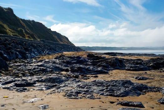 beautiful soft waves break on the black rocks at ballybunion beach in ireland