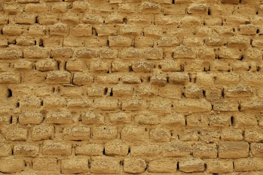 An old adobe mud brick wall showing signs of weathering