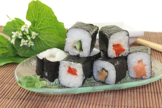 a glass bowl with sushi and fresh wasabi leaves
