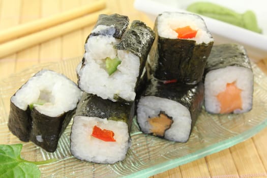 a glass bowl with sushi and fresh wasabi leaves