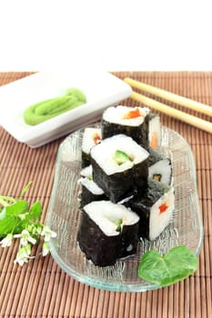 a glass bowl with sushi and fresh wasabi leaves