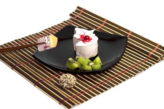white cake together with a kiwi on a rug, with chopsticks, the isolated background