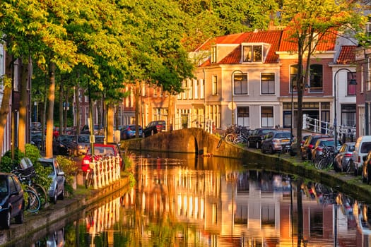 Delt canal with old houses and cars parked along on sunset. Delft, Netherlands