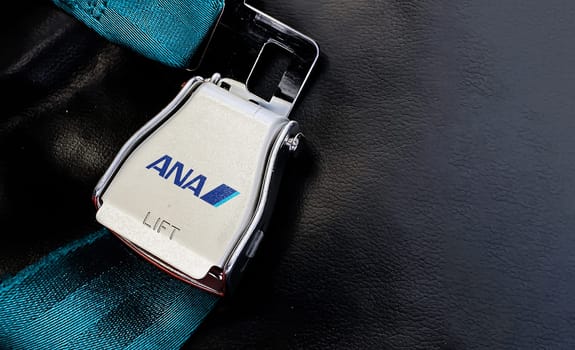 Tokyo, JAP, July 2019: green lap belt of an empty seat inside an airplane with the ANA All Nippon Airways logo printed on the metal. ANA is a Japanese airline